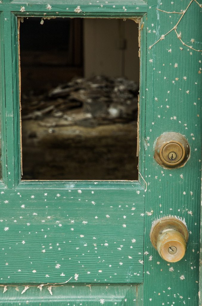 rustic door with hole showing decrepit interior room