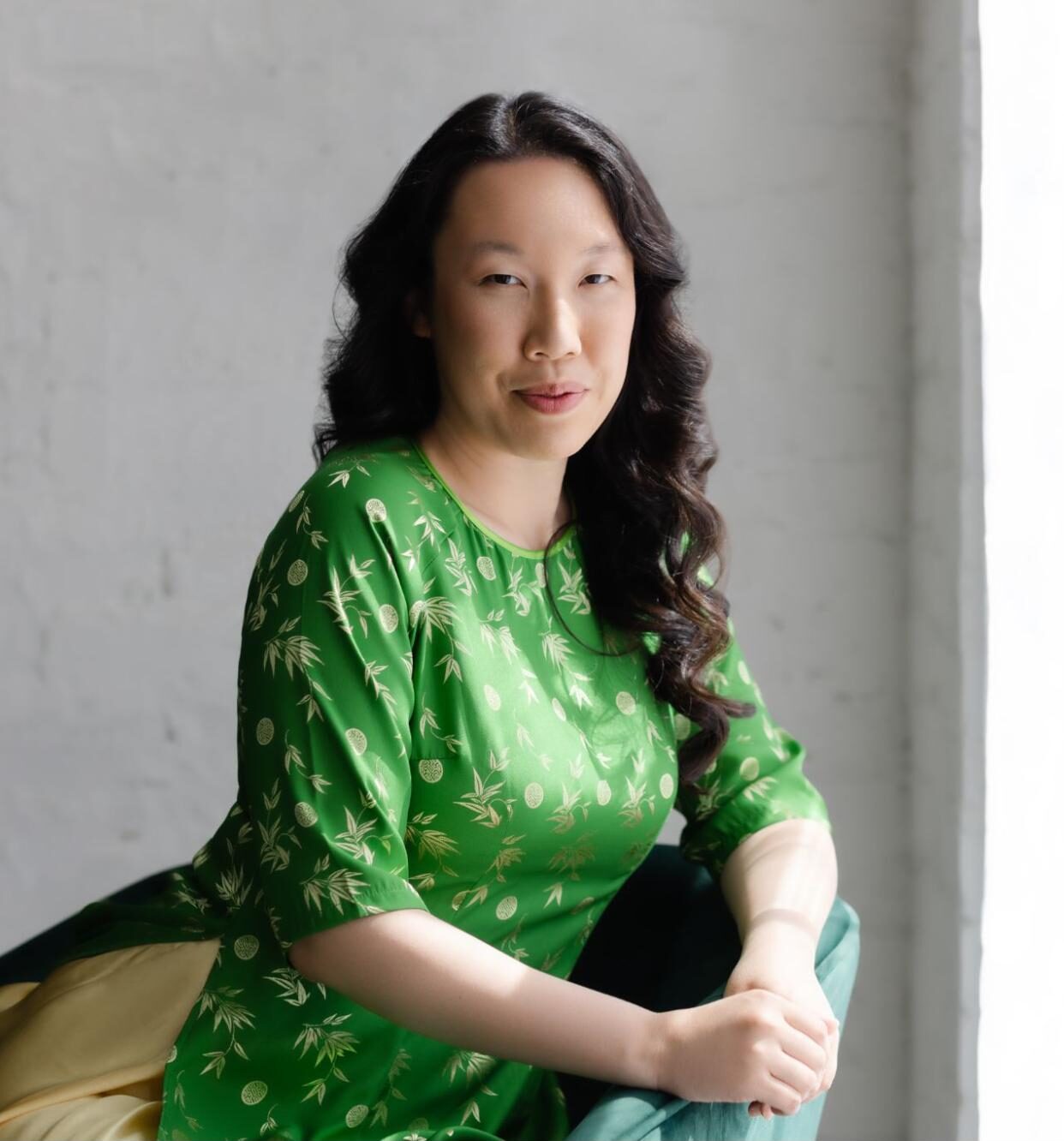Asian woman with long dark hair in green top.