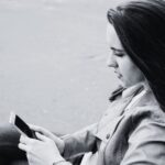 Black and white image of a woman looking at a phone.