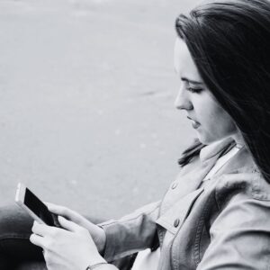Black and white image of a woman looking at a phone.