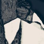 A black child hugs another black person and cries into their shoulder.