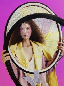 A mixed media image with a hot pink background that shows a woman in a yellow and pink blazer with strings laid over her face. The woman holds two mirror frames that are layered on top of each other, with multi-colored strings laying across the empty spaces of the frames and a purple ribbon hanging from the bottom of one.